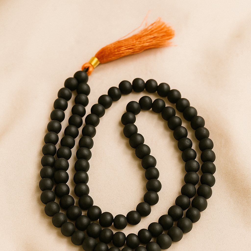 Black beaded ebony necklace with an orange tassel on a beige background